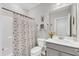 Bright bathroom features a shower-tub combo with curtain, grey vanity, and a decorative mirror at 1021 Shellbank Dr, Durham, NC 27703