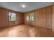 Bedroom features panel walls, hardwood floors, and natural light from two windows at 1051 Old Us 421, Lillington, NC 27546