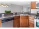 Kitchen area featuring wooden cabinetry, stainless steel dishwasher and oven, and stylish lighting fixture at 1116 Kingston Grove Drive Dr, Cary, NC 27519