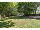 A lush backyard featuring mature trees, a storage shed, and partially covered ground at 112 Rectory St, Oxford, NC 27565