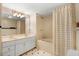 Bathroom with a double vanity, white cabinets, tiled floors, and a shower/tub combo at 125 W Pine St, Pine Level, NC 27568