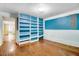 Bright bedroom with blue walls, hardwood floors, and open shelving at 125 W Pine St, Pine Level, NC 27568
