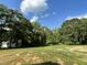 A view of the expansive backyard bordered by lush trees under a sunny, blue sky, perfect for relaxation or recreation at 175 Oakfield Trace Dr, Four Oaks, NC 27524