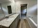 This bathroom features wood-look flooring, dual sinks with granite counters, and a soaking tub for relaxation at 175 Oakfield Trace Dr, Four Oaks, NC 27524