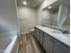 Bathroom featuring wood-look flooring, dual sinks with granite counters, and ample natural light from a window at 175 Oakfield Trace Dr, Four Oaks, NC 27524