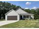 Charming single-story home featuring a front-facing garage and manicured lawn under a bright, cloud-dotted sky at 175 Oakfield Trace Dr, Four Oaks, NC 27524