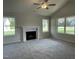 Bright living room featuring plush carpeting, a cozy fireplace, and abundant natural light from three large windows at 175 Oakfield Trace Dr, Four Oaks, NC 27524