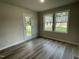 Bright living space featuring wood-look floors, two windows, and a glass panel door leading to the outdoors at 175 Oakfield Trace Dr, Four Oaks, NC 27524