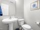Cozy half-bathroom featuring a pedestal sink, toilet, and framed floral artwork at 2011 Unbridled Dr, Knightdale, NC 27545