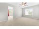 Bedroom with neutral carpet, ceiling fan, bright window with red curtains, and an open doorway at 2011 Unbridled Dr, Knightdale, NC 27545