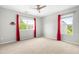 Bedroom with neutral carpet, red curtains, ceiling fan, and two bright windows at 2011 Unbridled Dr, Knightdale, NC 27545