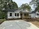 Charming single-story home featuring a welcoming front porch and newly paved driveway, complemented by lush green trees at 2309 Pinecroft Dr, Burlington, NC 27217