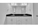Bright bathroom featuring dual sinks with black counters and white cabinets at 267 Ashley Woods Ct, Clayton, NC 27527