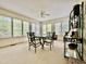 Bright sunroom with multiple windows, neutral carpet, ceiling fan, and an elegant dining set at 405 Foster Ln, Burlington, NC 27215
