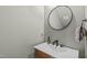 Modern half bathroom with a round mirror, sleek faucet, and stylish vanity with wood accents at 415 1St St, Apex, NC 27502