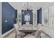 Dining room with dark blue accent wall, decorative lighting, and table set for six at 415 1St St, Apex, NC 27502