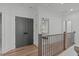 Upstairs hallway with wood floors, wooden railing, access to bedrooms and double-door closet at 415 1St St, Apex, NC 27502