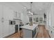 Open concept kitchen features white cabinets, center island with quartz countertops, stainless appliances and a modern light fixture at 415 1St St, Apex, NC 27502