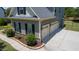 Three-car garage with white doors, complemented by a paved driveway and verdant landscaping around the house at 604 Nottely Pl, Cary, NC 27519
