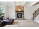 Living room featuring a stone fireplace with mantle, staircase, and neutral carpet at 604 Nottely Pl, Cary, NC 27519