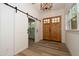 Bright foyer featuring wood-look flooring, barn door, a craftsman front door and modern light fixture at 690 Oaks Lane Rd, Timberlake, NC 27583
