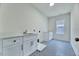 Well-lit laundry room with white cabinets, a sink, and patterned tile floor at 8011 Old Trail Dr, Durham, NC 27712