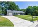 Inviting single story home with a long driveway and lush front lawn, framed by mature trees at 100 Honeysuckle Ln, Cary, NC 27513
