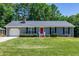 Charming single story home featuring a red front door, well-manicured lawn and mature trees at 100 Honeysuckle Ln, Cary, NC 27513