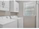 Functional laundry area featuring a window for light, storage cabinets, and modern washer/dryer at 100 Honeysuckle Ln, Cary, NC 27513