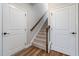 Carpeted staircase with wood railing between two white doors offers access to upper or lower levels at 100 Pronghorn Deer Ct, Garner, NC 27529