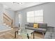 Sunlit living room featuring staircase, gray sofa, glass coffee table, and wood floors at 1002 Willow Dr # Apt 107, Chapel Hill, NC 27514