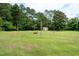 Large backyard with grass, a fire pit, and an outbuilding with a yellow door at 1008 Catsby Cir, Raleigh, NC 27603