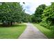 Long driveway leading to a house surrounded by mature trees and a green lawn at 1008 Catsby Cir, Raleigh, NC 27603