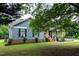 Charming home featuring blue siding, white trim, a yellow door and a landscaped front yard with mature trees at 1008 Catsby Cir, Raleigh, NC 27603