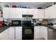 The charming kitchen features tile backsplash, black appliances and white cabinets at 1008 Catsby Cir, Raleigh, NC 27603
