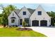 Stunning white brick home featuring a manicured lawn, a two car garage and a black roof at 1012 Lily Claire Ln, Fuquay Varina, NC 27526
