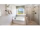 Relaxing bathroom with a soaking tub below a window and a glass enclosed shower with built-in shelves at 1017 Dillon Lake Dr, Knightdale, NC 27545