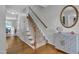 Hallway with hardwood floors and carpeted stairs, complemented by a decorative cabinet and mirror at 102 Lake Meadow Dr, Apex, NC 27502
