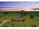 A ranch-style home with a brick facade, large front yard, mature trees, and a backdrop of lush greenery at twilight at 1035 Aquilla Rd, Benson, NC 27524
