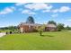 Charming brick home with a well-manicured lawn and mature trees on a sunny day at 1035 Aquilla Rd, Benson, NC 27524