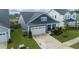 Aerial view of a charming blue house with a white garage, lush green lawn, and an inviting driveway at 1104 Briar Gate Dr, Holly Springs, NC 27540