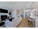 Open-concept living room with hardwood floors, a fireplace, and a seamless flow to the modern kitchen at 113 Seagraves Creek Ln, Holly Springs, NC 27540