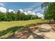 Scenic golf course view featuring lush green fairway, mature trees, a sand trap, and a concrete golf cart path at 1149 The Preserve Trl, Chapel Hill, NC 27517