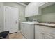 Bright laundry room with white cabinets, appliances, tile floor and sage green walls at 1149 The Preserve Trl, Chapel Hill, NC 27517