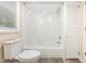White tiled bathtub and shower with a matching toilet and gray wood-look flooring at 121 Lena Ct, Burlington, NC 27217