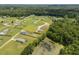 Wide aerial showcases a neighborhood with green lawns, houses, and a pond, surrounded by lush trees at 130 Ruby Trl, Roxboro, NC 27574