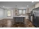 A kitchen features a center island, stainless steel appliances, and wood grain cabinets against woodgrain flooring at 130 Ruby Trl, Roxboro, NC 27574