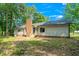 Backyard featuring a brick chimney, wood staircase, and siding, surrounded by lush trees and foliage at 1308 Broken Branch Ct, Raleigh, NC 27610