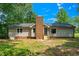 Backyard featuring a brick chimney, gray siding, and green foliage, complete with a sunny view and small staircase at 1308 Broken Branch Ct, Raleigh, NC 27610
