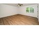 Bright bedroom with wood-look flooring, ceiling fan, neutral walls, white trim, and a window with a leafy view at 1308 Broken Branch Ct, Raleigh, NC 27610